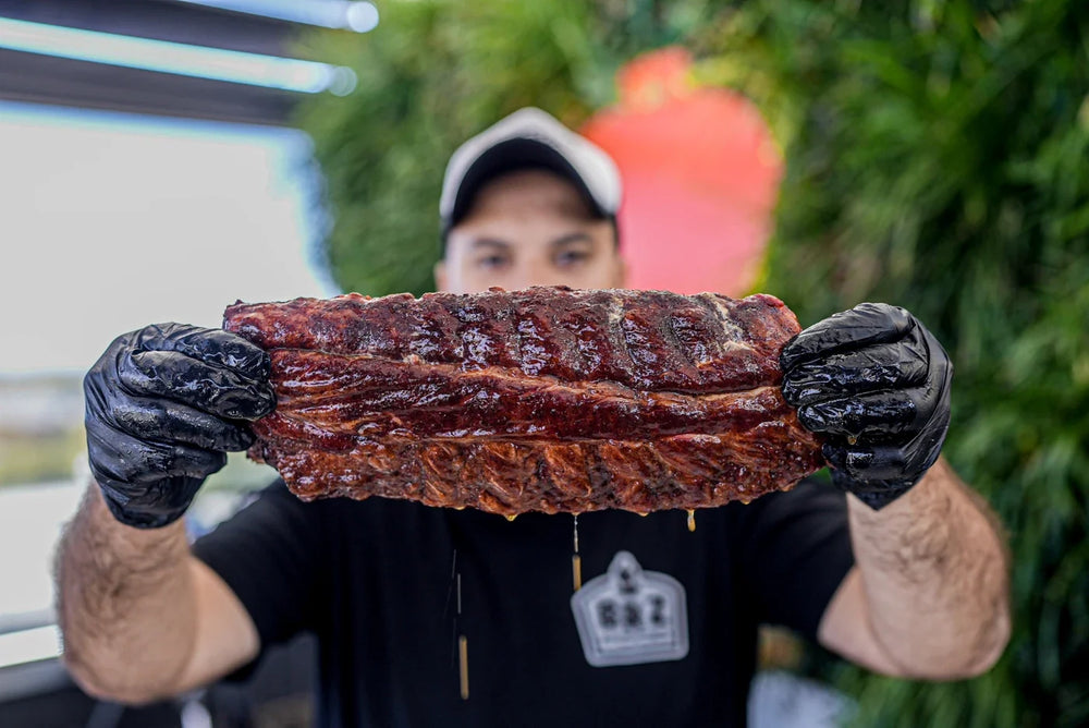 Adriano holding a rack of glazed smoked pork ribs